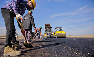 photo of workers laying asphalt on roadway